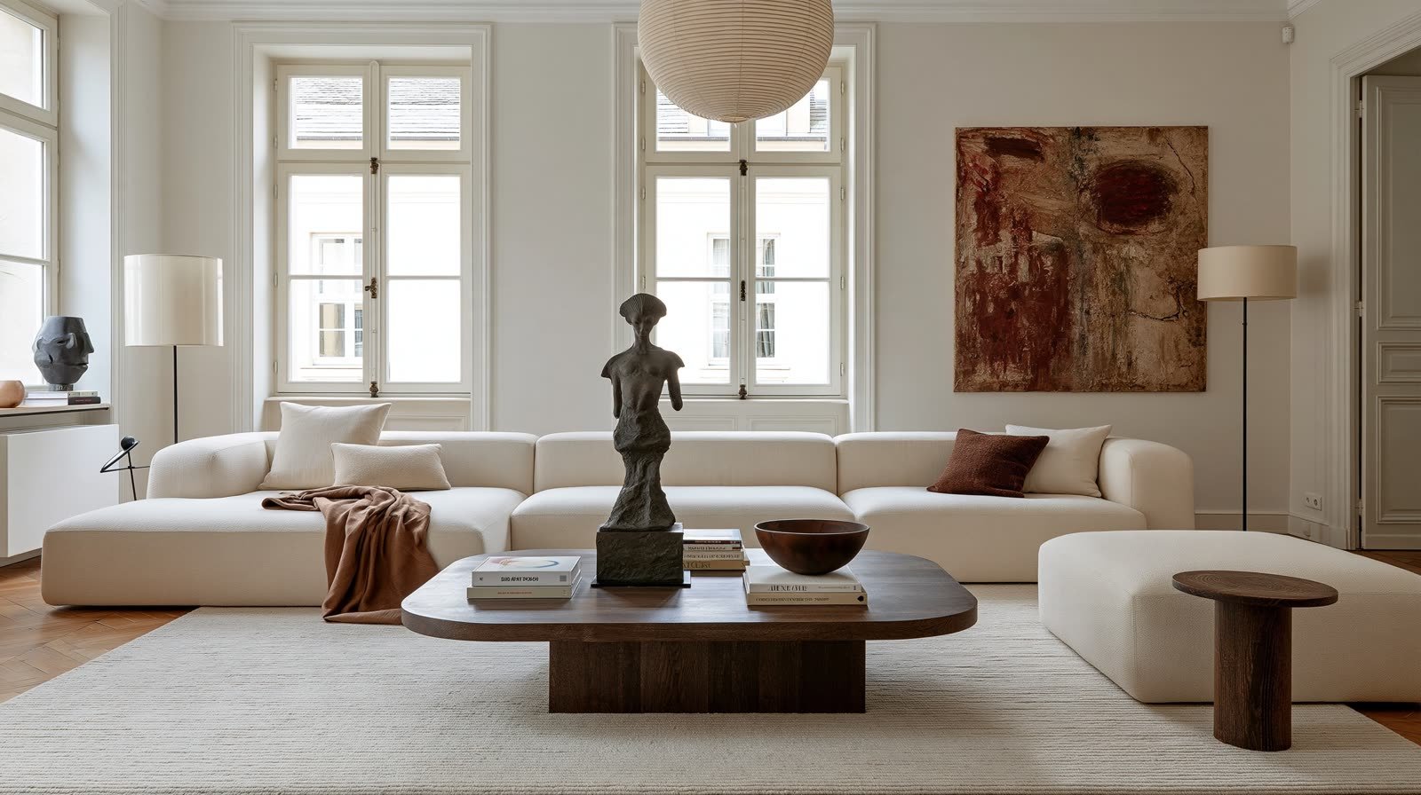 Un grand salon clair, une toile abstraite au mur et une statuette de bronze posée sur la table basse.