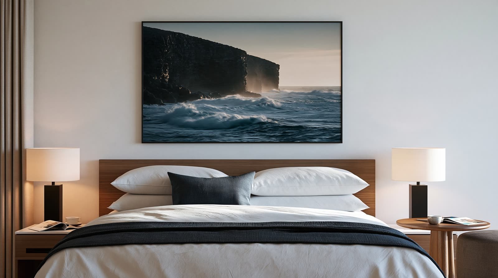 Une falaise noire au-dessus d’une mer sombre, photographie encadrée au-dessus d’un lit.